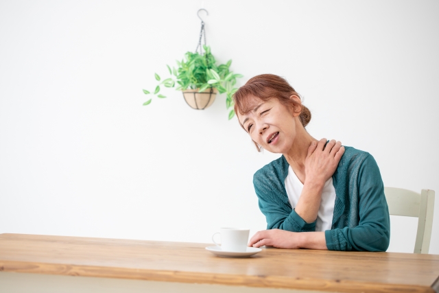 テーブルで肩を押さえる女性