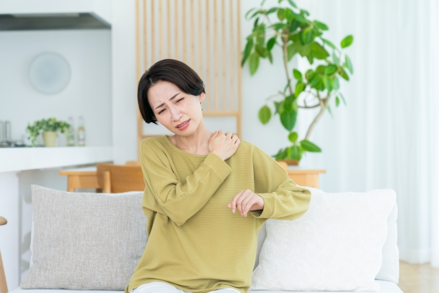 ソファに座って肩を押さえる女性